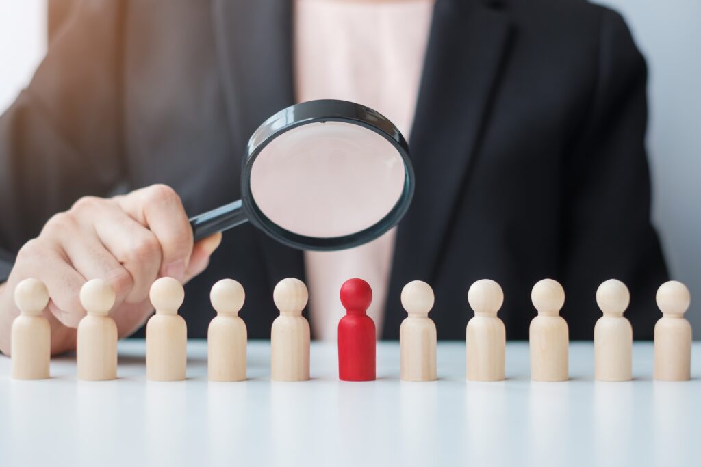 Businesswoman hand holding magnifying glass for recruiting leade