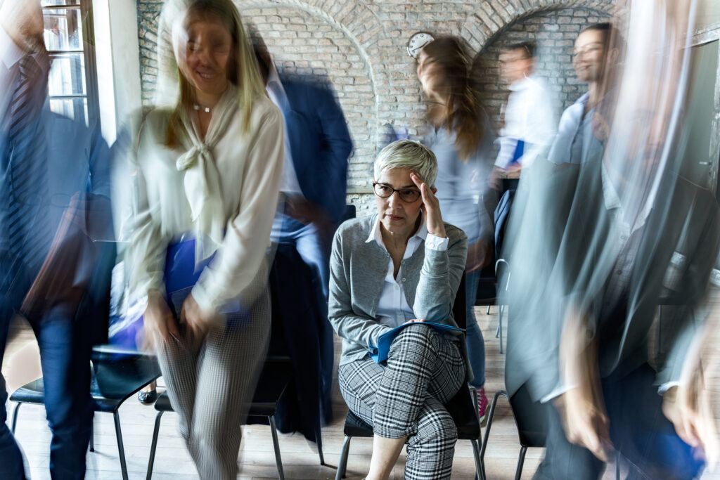 Female entrepreneur having a headache on a seminar among her colleagues in blurred motion